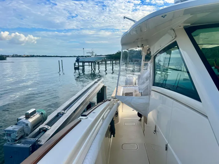  Yacht Photos Pics 2020 Scout 420 LXF boat docked by serene waterfront under blue sky.