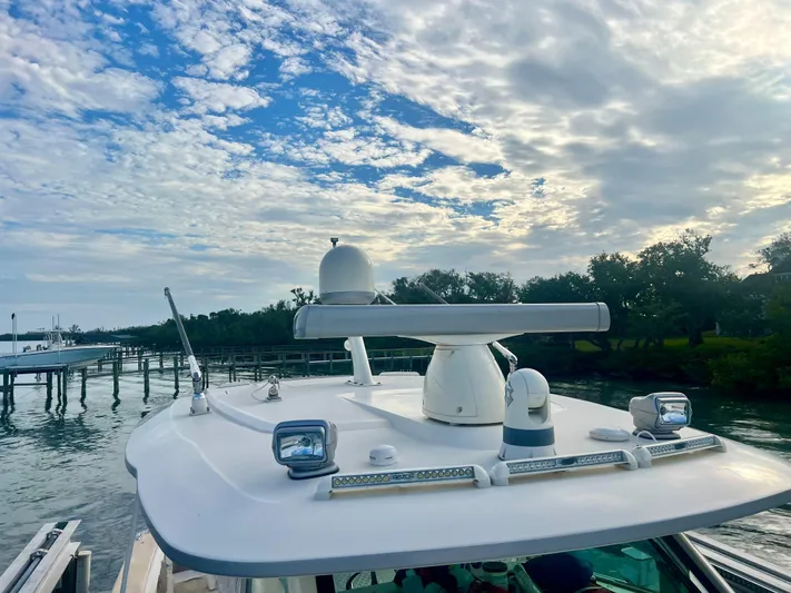  Yacht Photos Pics 2020 Scout 420 LXF boat docked by scenic waterfront under cloudy sky.