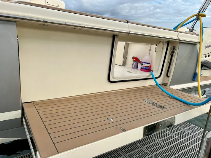 Yacht Photos Pics 2020 Scout 420 LXF boat deck with storage compartment and cleaning supplies.