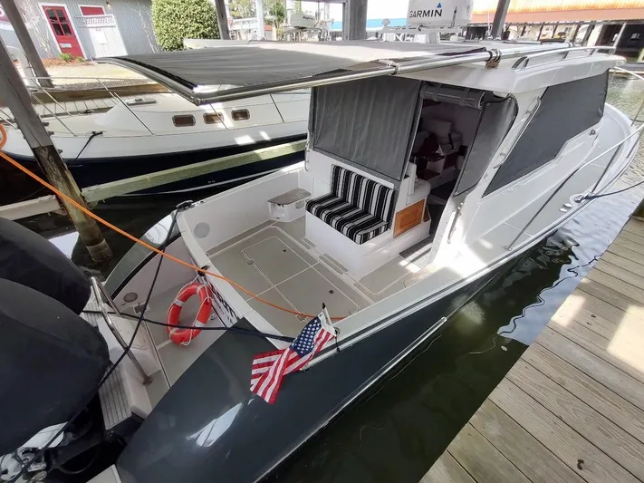 Singularity Yacht Photos Pics 2022 True North 34 boat docked, featuring striped seating and American flag.