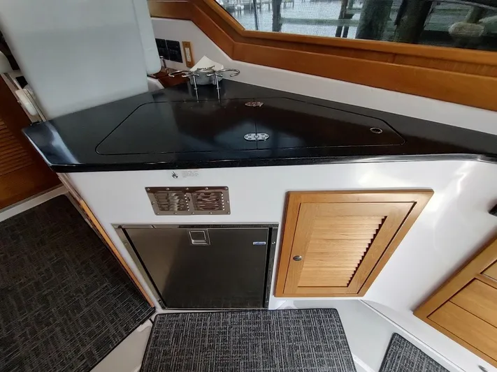 Singularity Yacht Photos Pics Modern kitchen area in a 2022 True North 34 boat, featuring sleek countertops and wooden cabinetry.