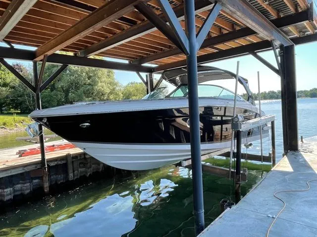  Yacht Photos Pics 2016 Regal 3200 Bowrider boat docked under a wooden canopy by the water.
