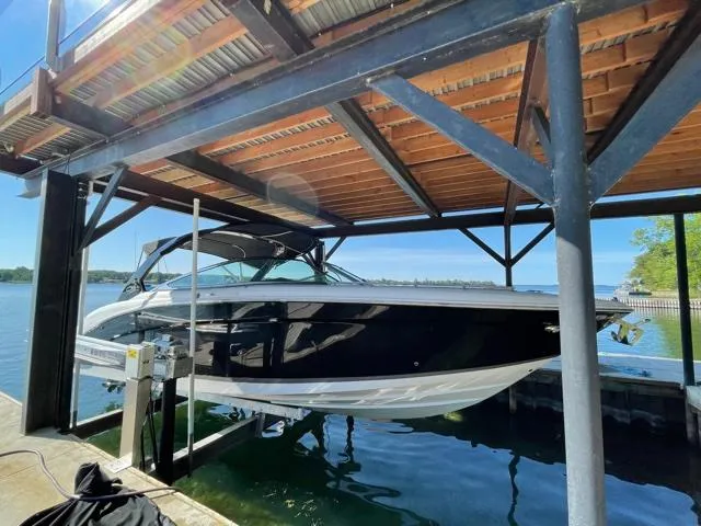  Yacht Photos Pics 2016 Regal 3200 Bowrider boat docked under a wooden canopy on a sunny day.