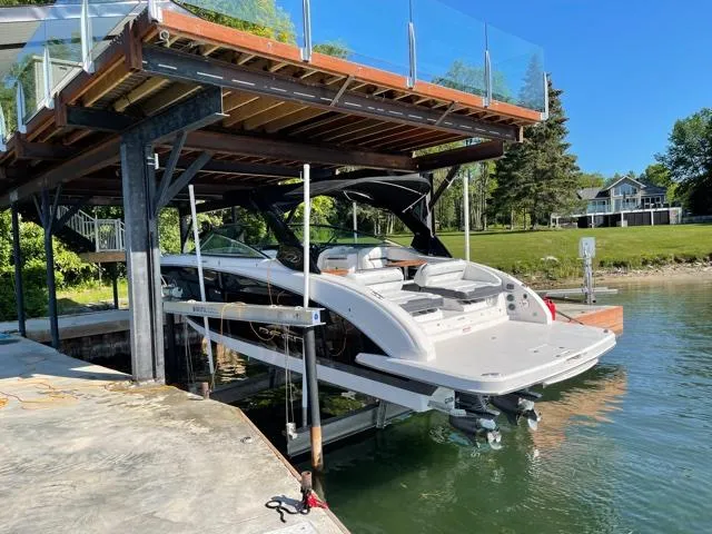  Yacht Photos Pics 2016 Regal 3200 Bowrider docked on a lift by a lakeside property.