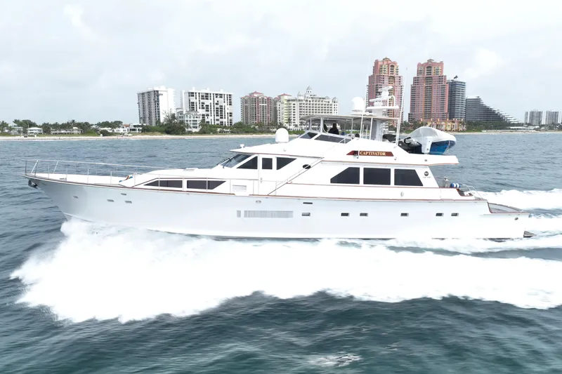 Captivator Yacht Photos Pics 1984 Palmer Johnson Motor Yacht cruising near a coastal city skyline.