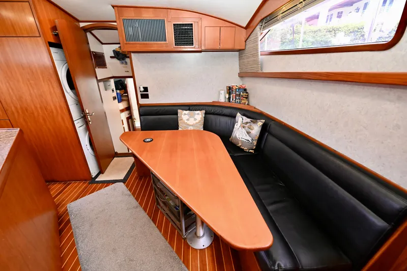 Captivator Yacht Photos Pics Interior of 1984 Palmer Johnson Motor Yacht with wooden table and black leather seating.