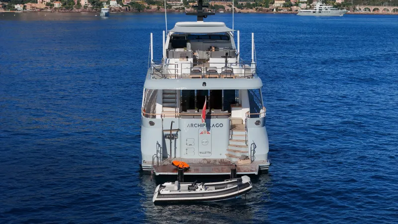 Archipelago Yacht Photos Pics Moonen Displacement Yacht 2005 on calm blue water, rear view with small boat attached.