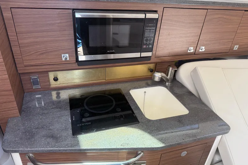  Yacht Photos Pics 2021 Boston Whaler 325 Conquest kitchen with microwave, sink, and stovetop.