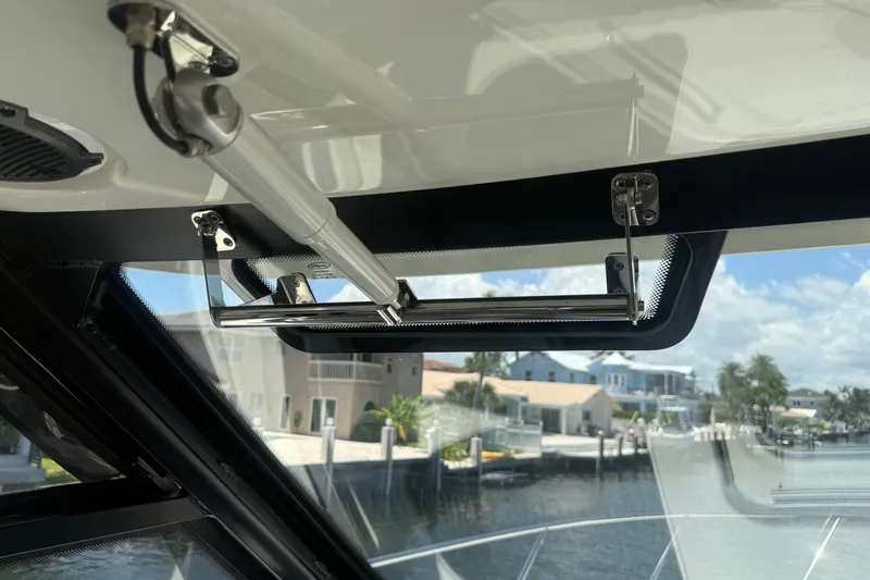  Yacht Photos Pics 2021 Boston Whaler 325 Conquest boat interior, showcasing window mechanism and waterfront view.