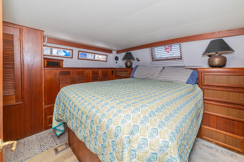 Cynful One Yacht Photos Pics Cozy bedroom in 1982 Viking 44 Motor Yacht with wood paneling and patterned bedding.