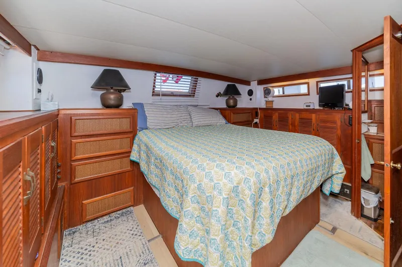 Cynful One Yacht Photos Pics 1982 Viking 44 Motor Yacht bedroom with wood paneling, cozy bed, and nautical decor.