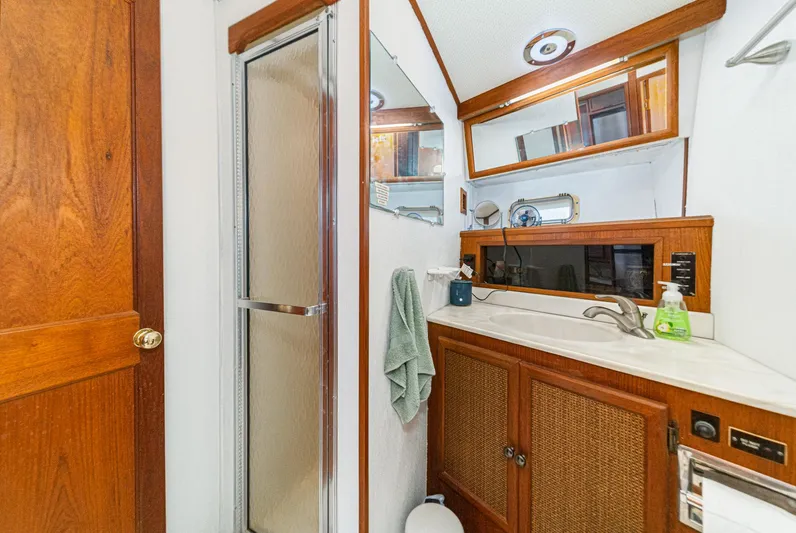Cynful One Yacht Photos Pics 1982 Viking 44 Motor Yacht bathroom with shower, wooden cabinetry, and sink area.