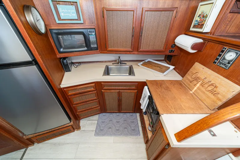 Cynful One Yacht Photos Pics 1982 Viking 44 Motor Yacht kitchen with wood cabinetry, sink, microwave, and refrigerator.