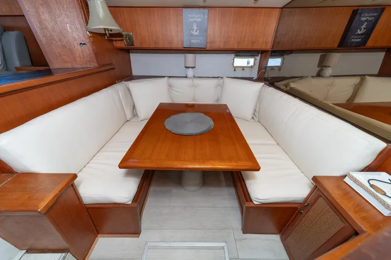 Cynful One Yacht Photos Pics 1982 Viking 44 Motor Yacht interior with wooden dining table and cushioned seating.