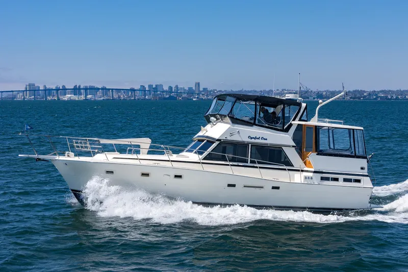 Cynful One Yacht Photos Pics 1982 Viking 44 Motor Yacht cruising on open water with city skyline in background.