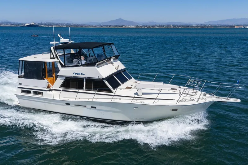 Cynful One Yacht Photos Pics 1982 Viking 44 Motor Yacht cruising on open water, clear sky, distant mountains.