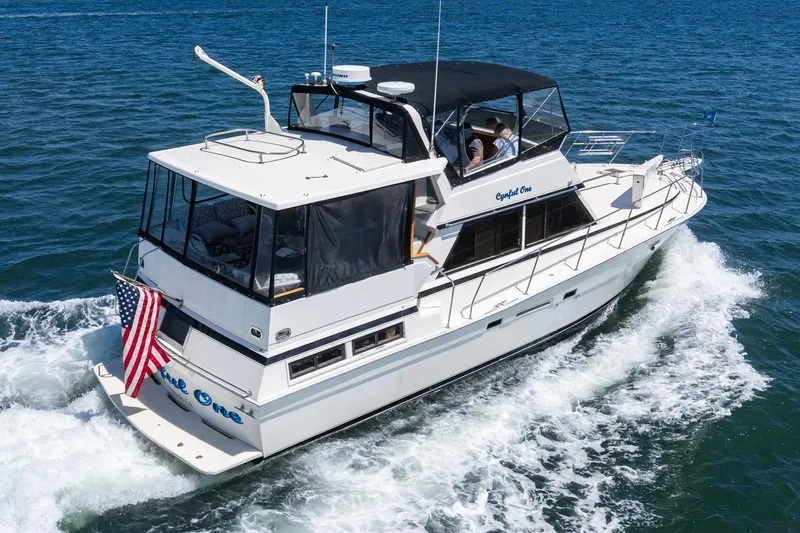 Cynful One Yacht Photos Pics 1982 Viking 44 Motor Yacht cruising on open water with American flag displayed.
