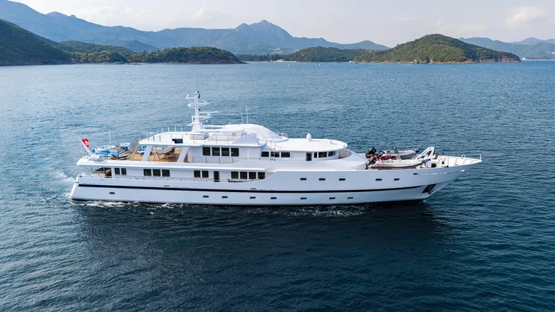 Grand Cru Yacht Photos Pics Luxurious 1995 Baglietto 49M yacht cruising in scenic waters with mountainous backdrop.