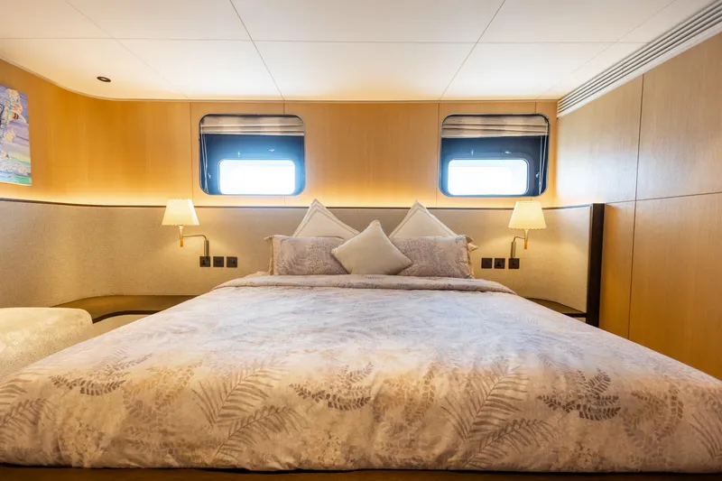 Grand Cru Yacht Photos Pics Luxurious bedroom interior on a 1995 Baglietto 49M yacht, featuring elegant bedding and soft lighting.