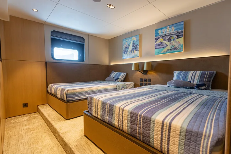 Grand Cru Yacht Photos Pics Luxurious twin bedroom on 1995 Baglietto 49M yacht with striped bedding and modern decor.