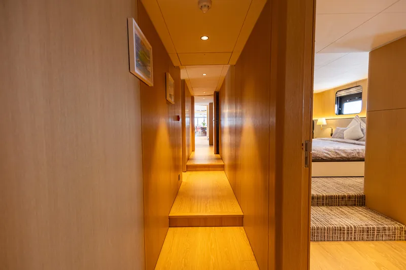 Grand Cru Yacht Photos Pics Luxurious interior hallway of 1995 Baglietto 49M yacht with wooden finishes and cozy bedroom.