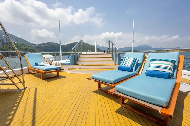 Grand Cru Yacht Photos Pics Luxurious deck of 1995 Baglietto 49M yacht with blue sun loungers and scenic ocean view.