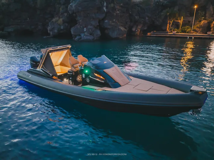  Yacht Photos Pics 2025 SPX RIB 32 Dinette boat illuminated on serene water at dusk.