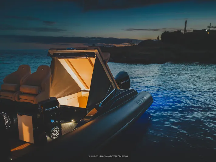  Yacht Photos Pics 2025 SPX RIB 32 Dinette boat illuminated at dusk on calm waters.