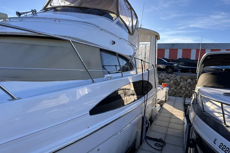 Allegedly Yacht Photos Pics 2000 Carver 396 Motor Yacht docked beside another boat, under clear blue sky.