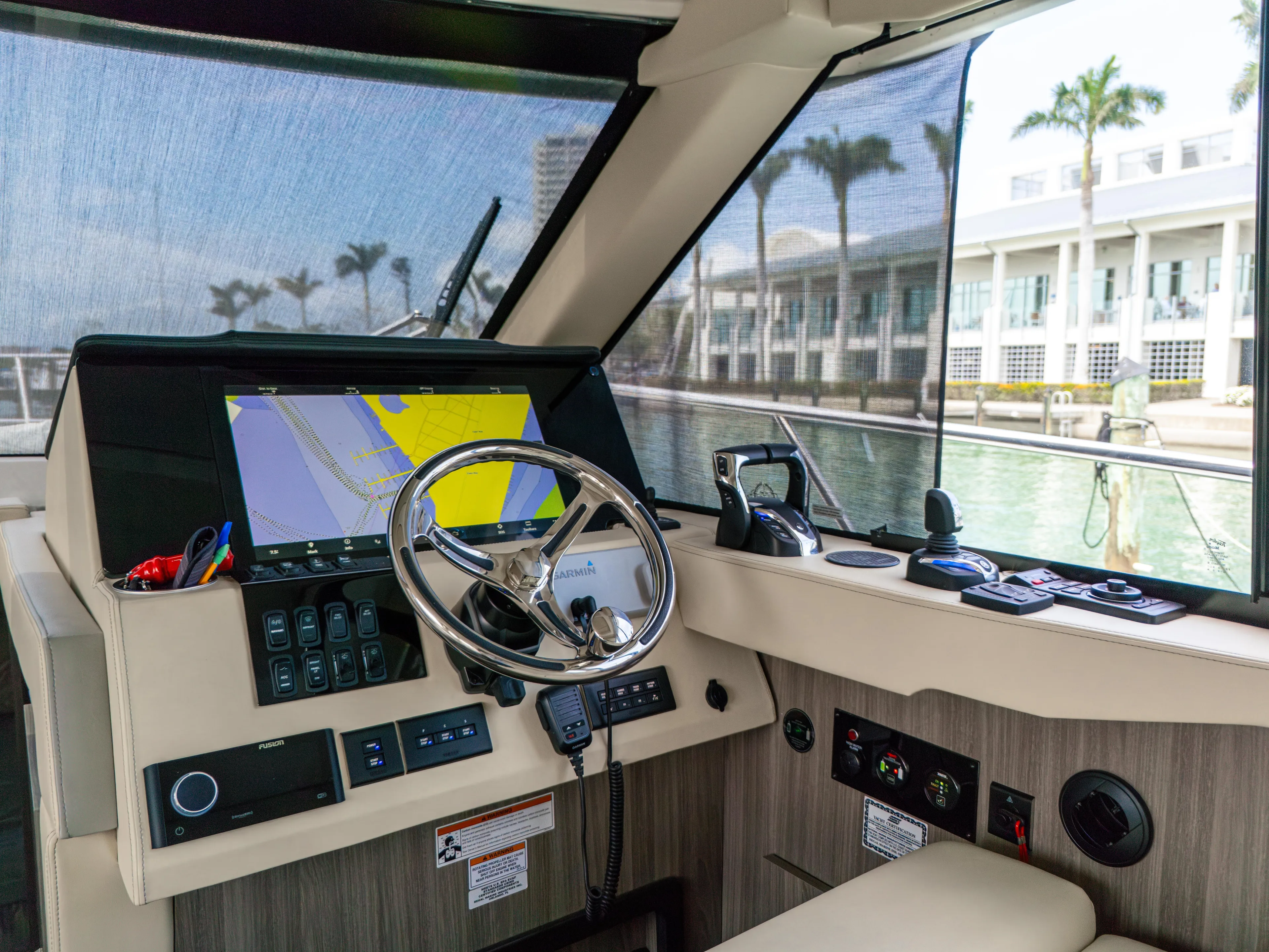  Yacht Photos Pics 2023 Regal 38 FXO yacht helm with navigation display and controls, docked near palm trees.