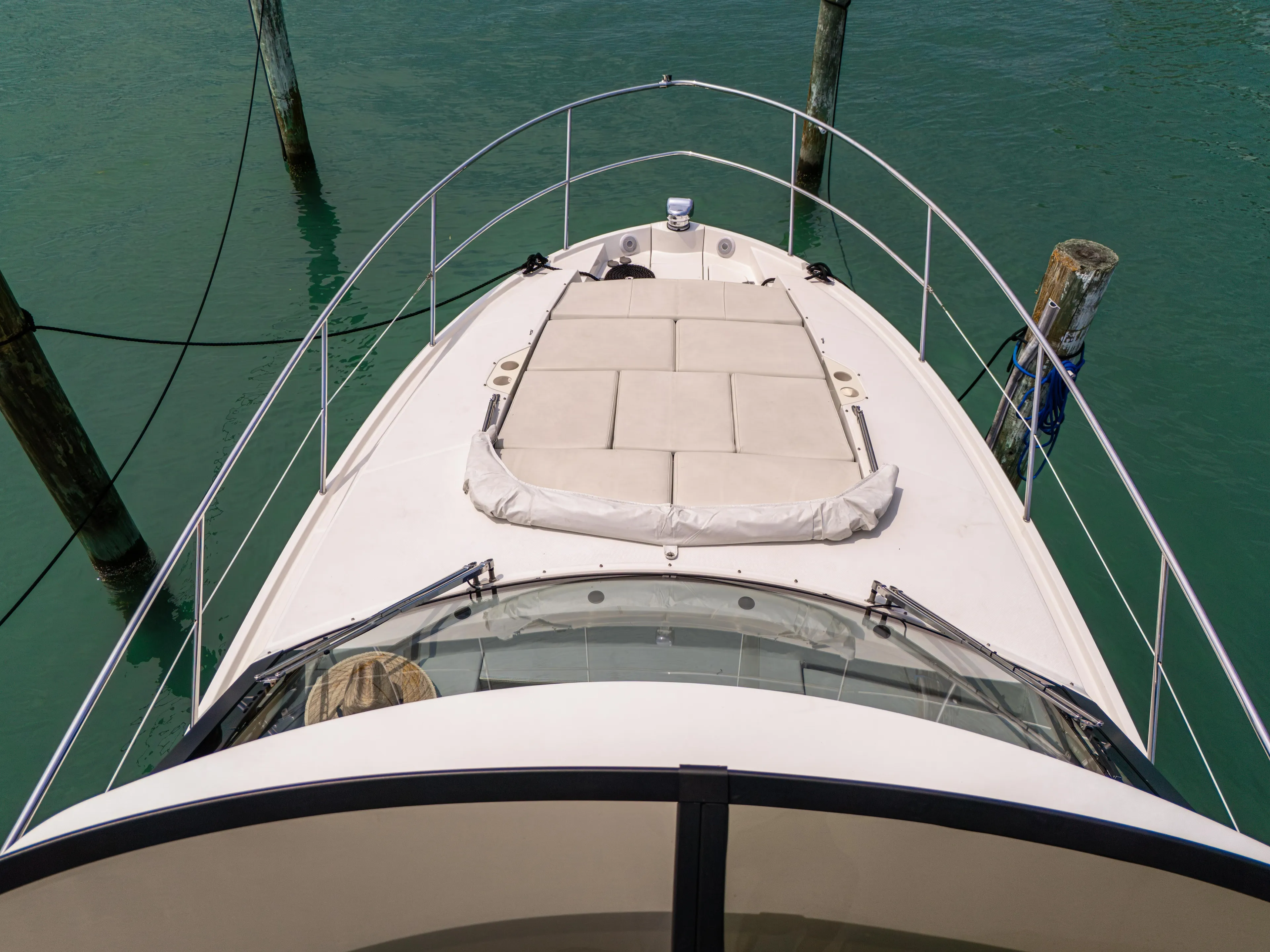  Yacht Photos Pics 2023 Regal 38 FXO yacht bow with sunpad, docked in clear water.