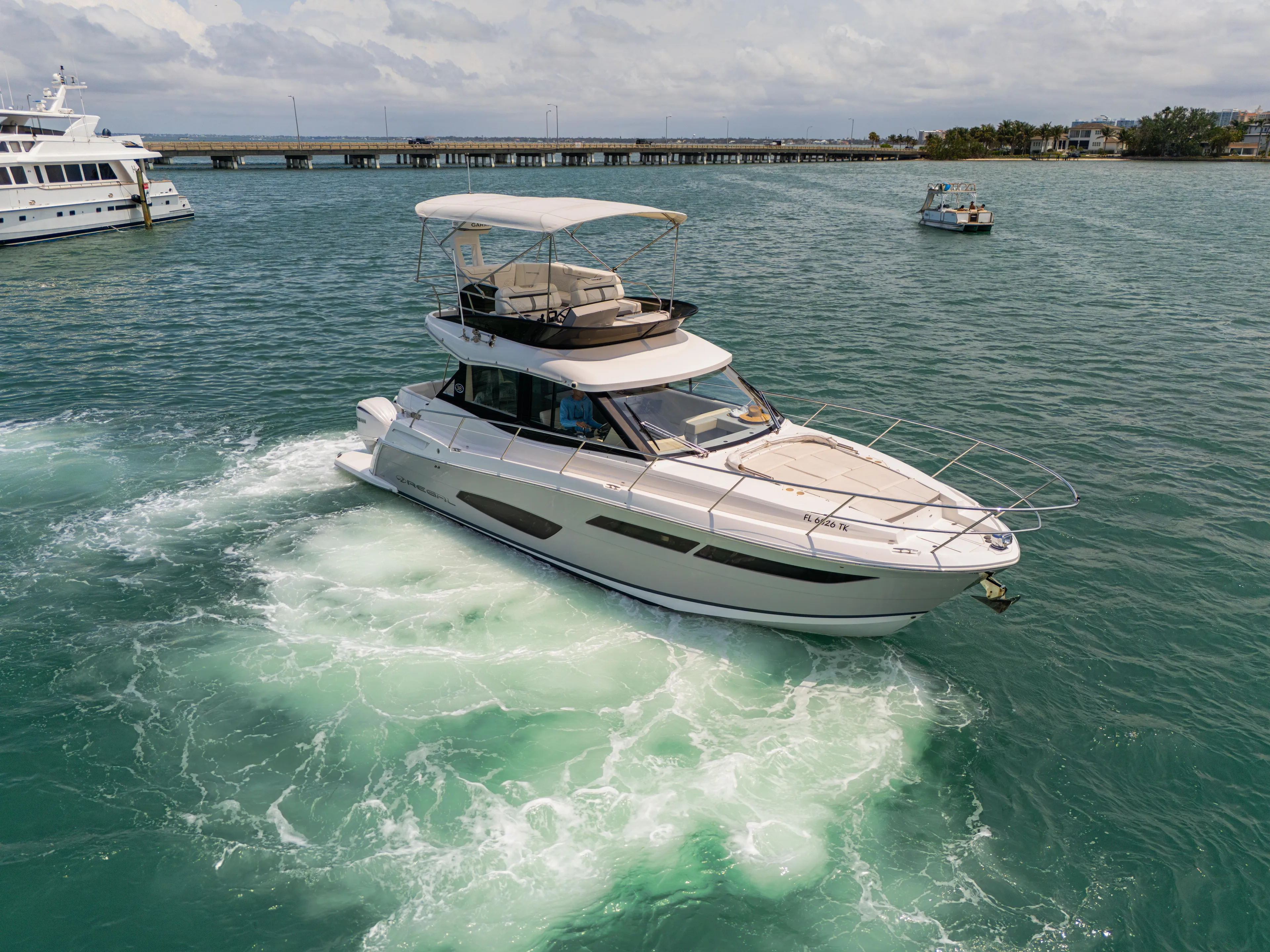  Yacht Photos Pics 2023 Regal 38 FXO yacht cruising on open water with bridge in background.