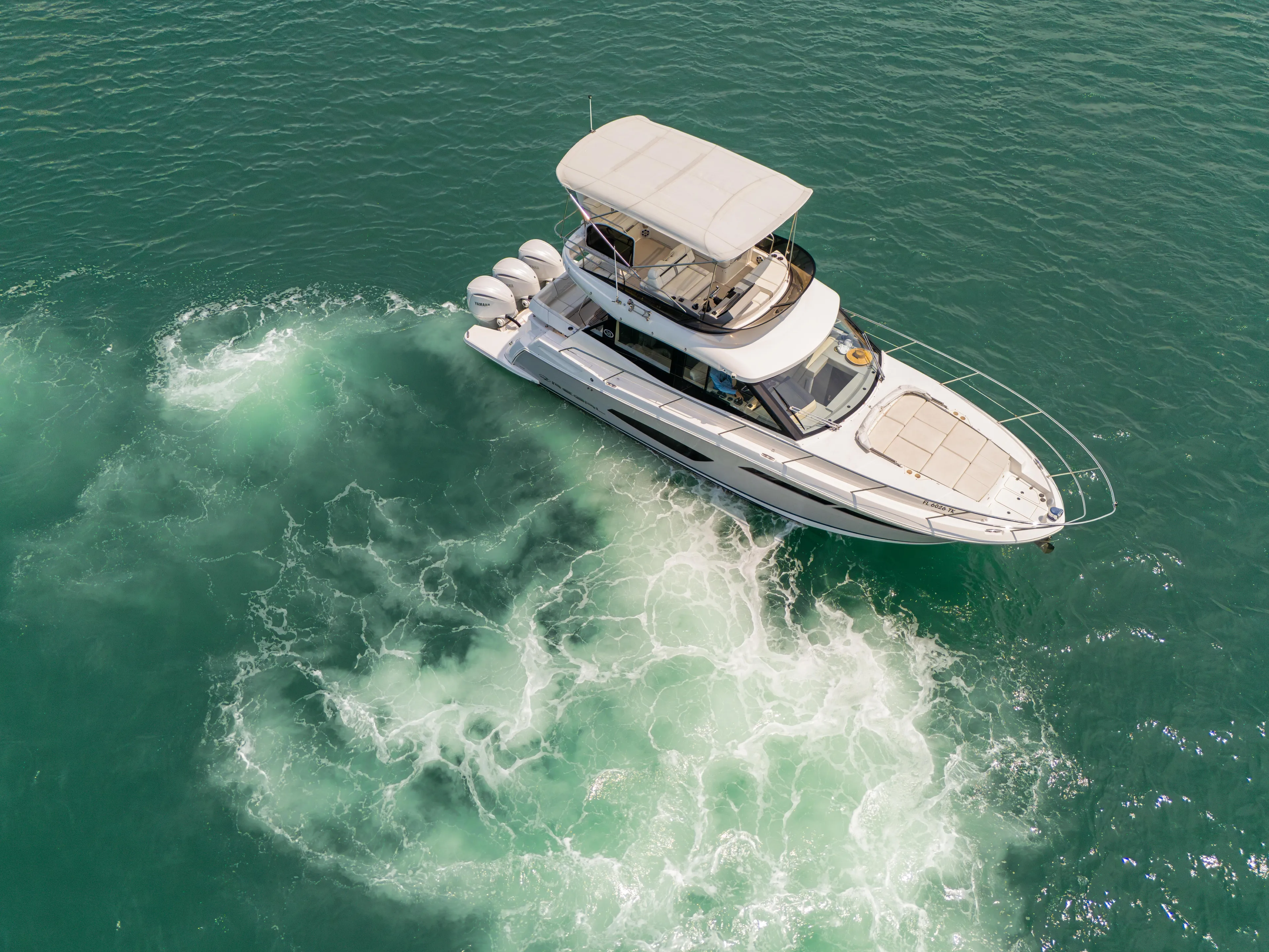  Yacht Photos Pics 2023 Regal 38 FXO yacht cruising in clear turquoise waters, aerial view.