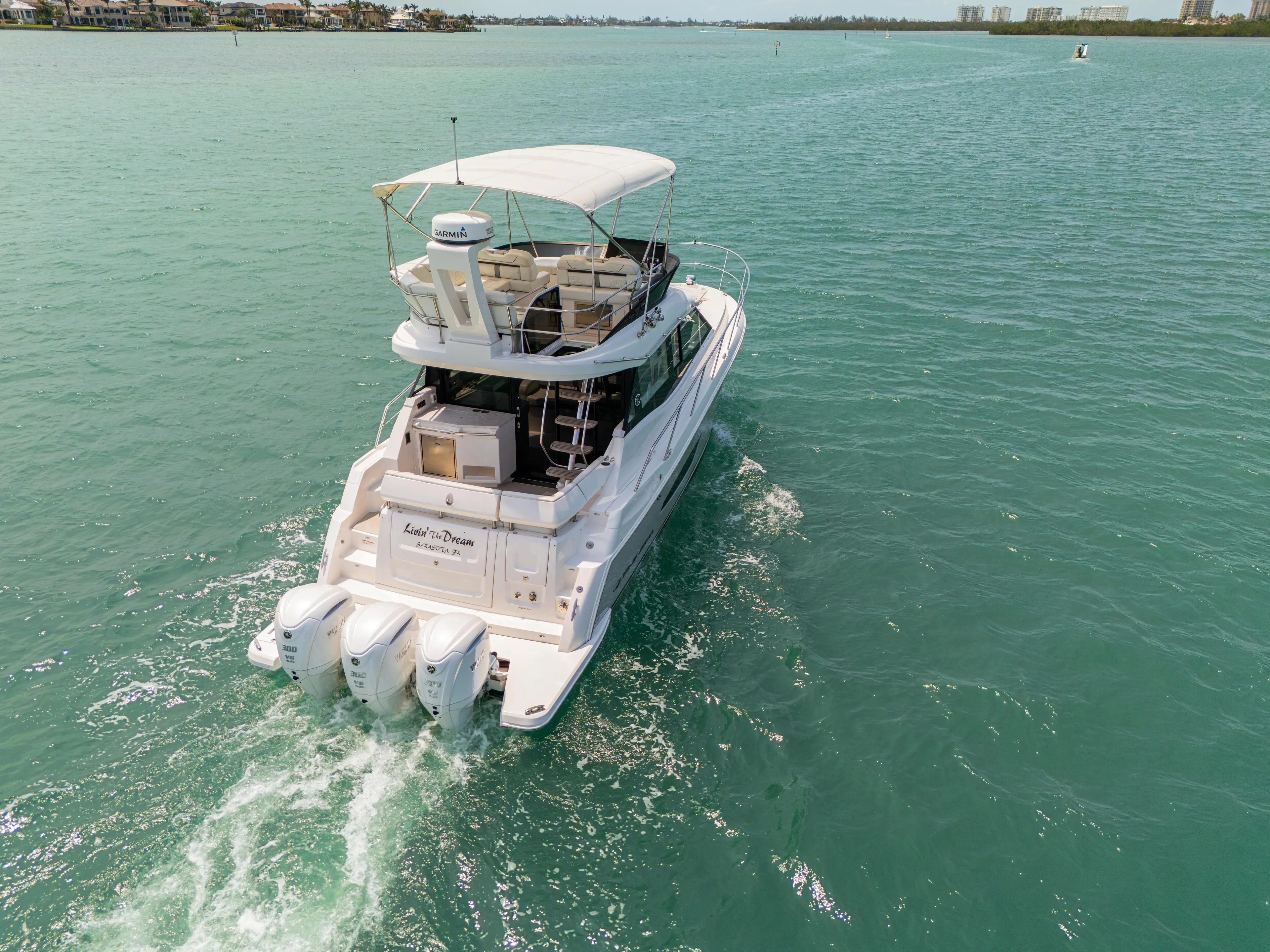  Yacht Photos Pics 2023 Regal 38 FXO yacht cruising on turquoise waters, rear view.