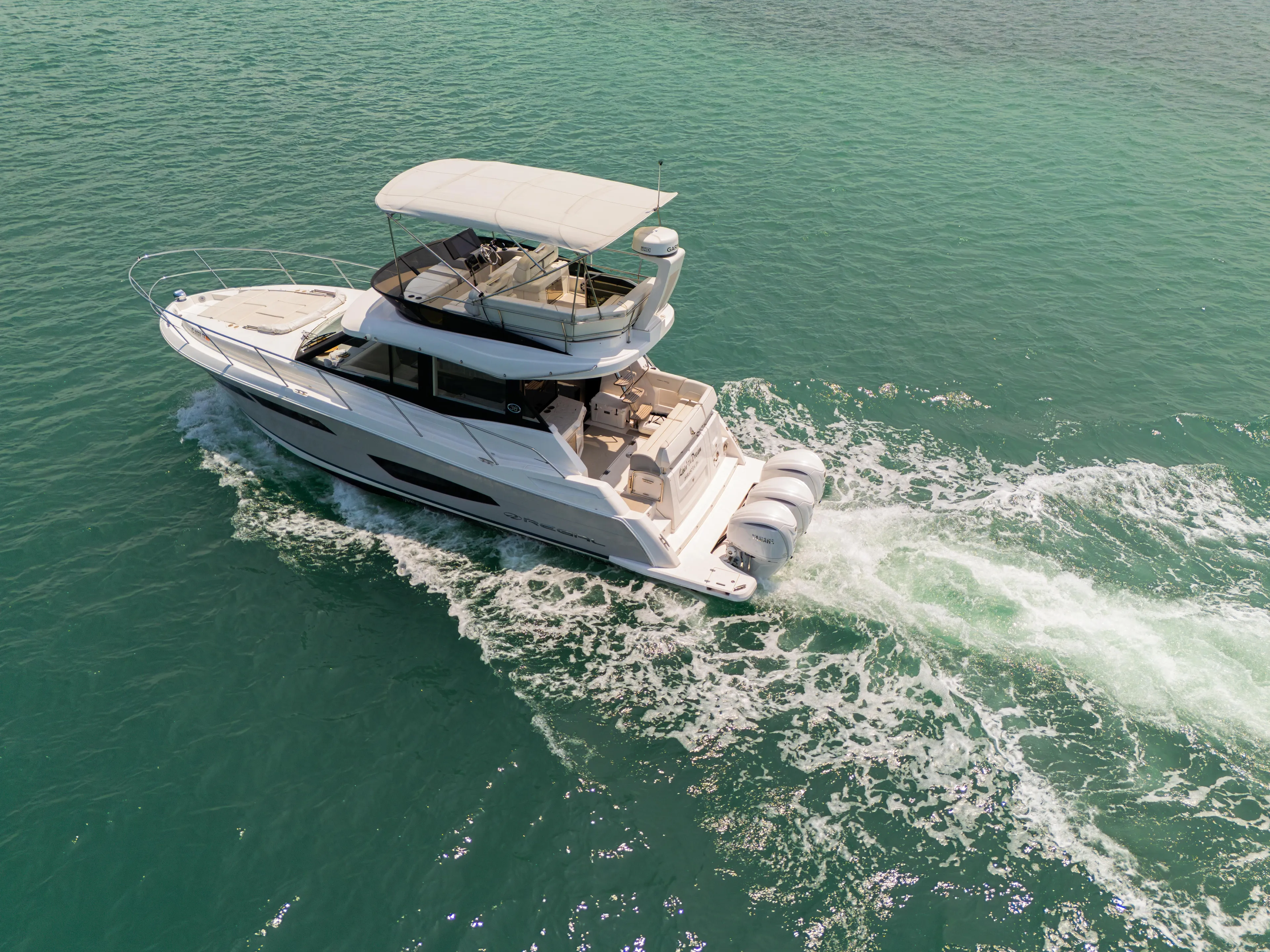  Yacht Photos Pics 2023 Regal 38 FXO yacht cruising on turquoise water, aerial view.