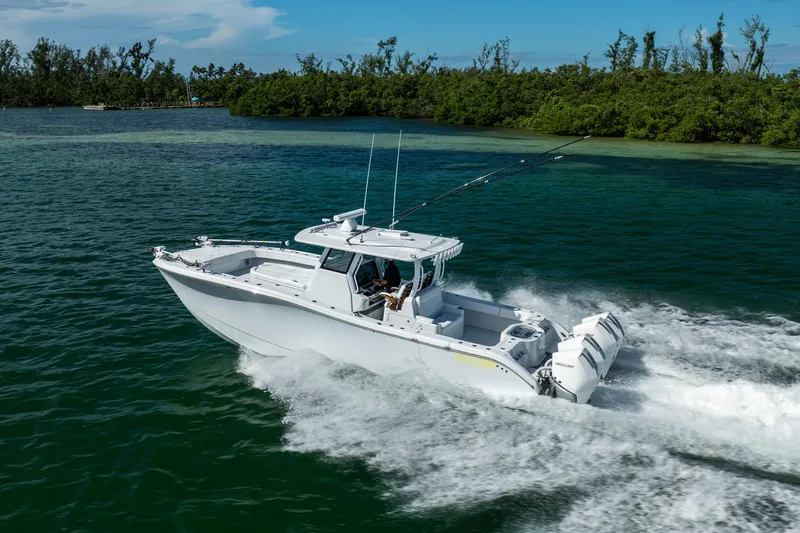  Yacht Photos Pics 2024 Costa Custom Boats 34 SV cruising on clear blue water near lush green shoreline.