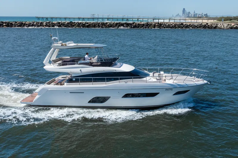 Sublime Yacht Photos Pics 2021 Ferretti Yachts 550 cruising on open water near a coastal city skyline.