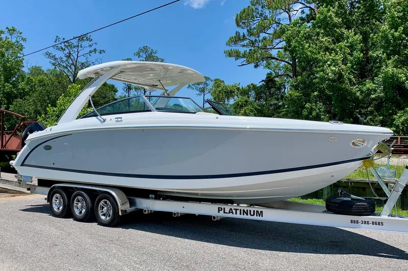 Drama Free Yacht Photos Pics 2022 Cobalt R30 boat on trailer, parked outdoors with trees in the background.