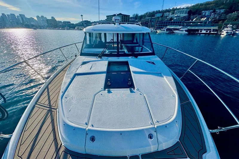  Yacht Photos Pics 2024 Jeanneau NC 1095 Coupe Series 2 on water, city skyline in background.