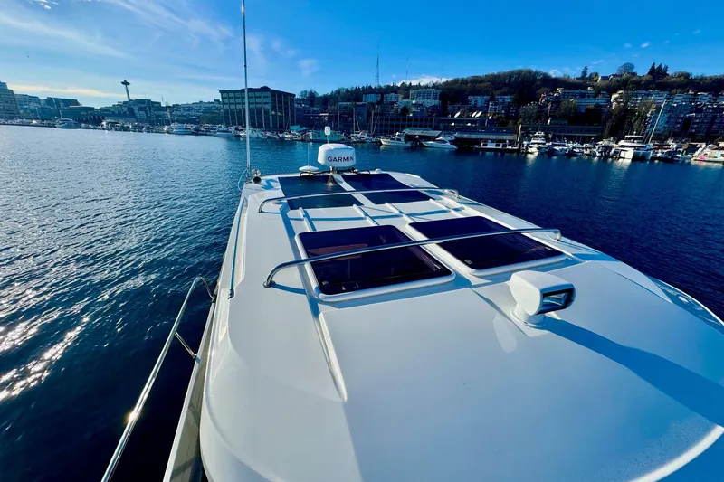  Yacht Photos Pics 2024 Jeanneau NC 1095 Coupe Series 2 on water, cityscape in background.