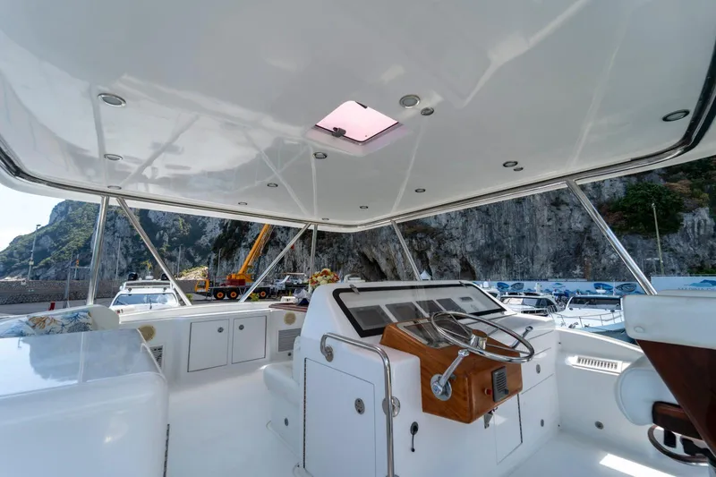  Yacht Photos Pics Flybridge of 2006 Vicem 54 Classic yacht with steering wheel and controls, docked near rocky cliffs.