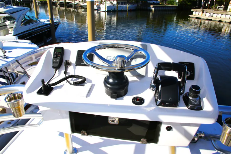 New! Hybrid Design Yacht Photos Pics Century NAV4100 CC-H (Twins) 2025 boat helm with steering wheel and controls, docked by the water.
