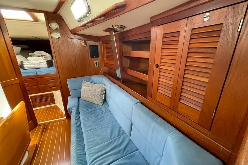 "snapdragon" Yacht Photos Pics Cozy interior of 1999 Tartan 4100 yacht with blue sofa and wooden cabinetry.