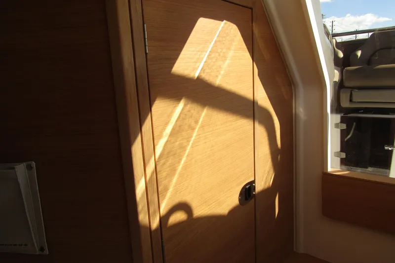  Yacht Photos Pics Interior of 2025 Nimbus Tender 9, featuring wooden door and sunlight casting shadows.