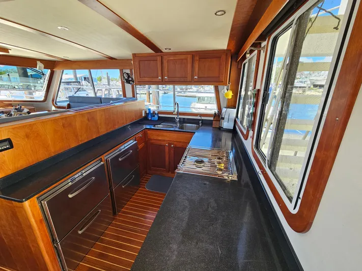 Audrey Louisa Yacht Photos Pics 2012 Maine Cat Power Cat 47 kitchen with wooden cabinets, black countertops, and marina view.