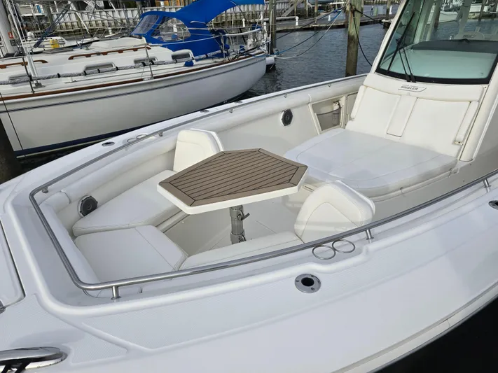  Yacht Photos Pics Boston Whaler 350 Outrage 2015 boat with spacious seating and table in marina setting.