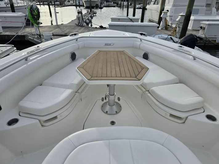  Yacht Photos Pics 2015 Boston Whaler 350 Outrage boat with cushioned seating and wooden table in marina.