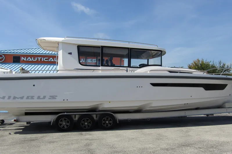  Yacht Photos Pics 2025 Nimbus Commuter 11 boat on trailer, parked outdoors under clear blue sky.