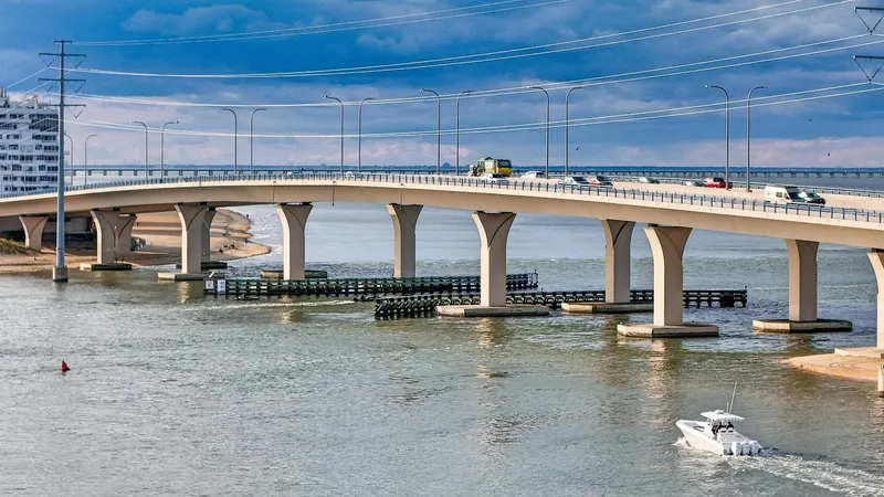  Yacht Photos Pics A 2022 Fountain 38TE boat cruising under a modern bridge on a sunny day.