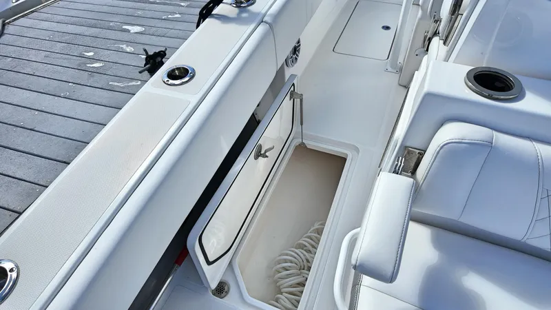  Yacht Photos Pics Open storage compartment on 2022 Fountain 38TE boat with white seating and dock view.